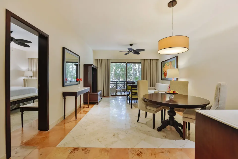 Royal Suite living area with dining table, balcony and bedroom doorway at Occidental at Xcaret Destination.