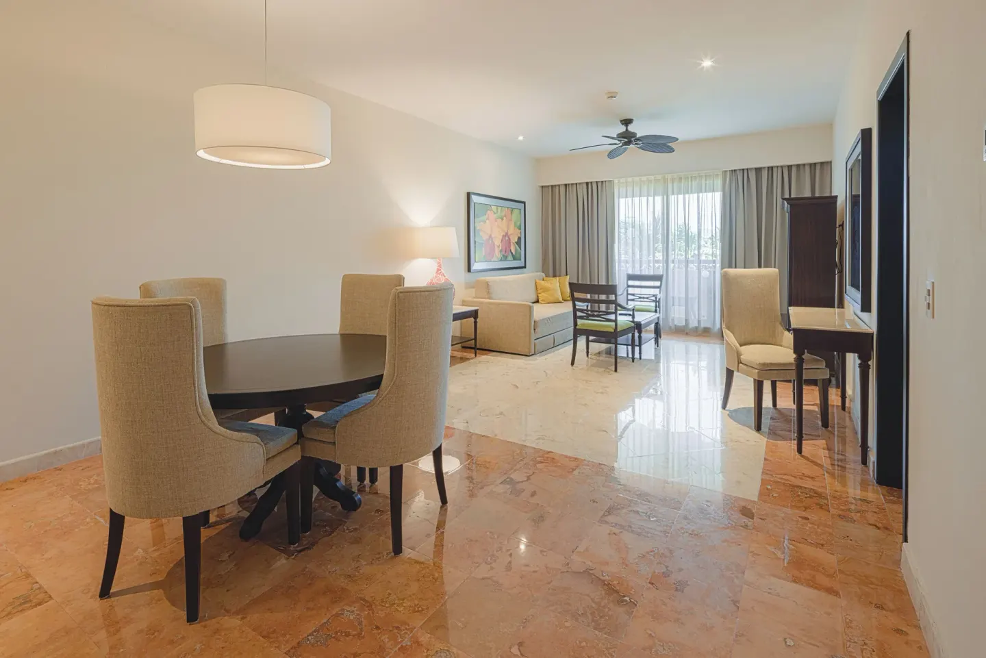 Royal Suite living room with dining table, sofa, desk and balcony curtains at Occidental at Xcaret Destination.