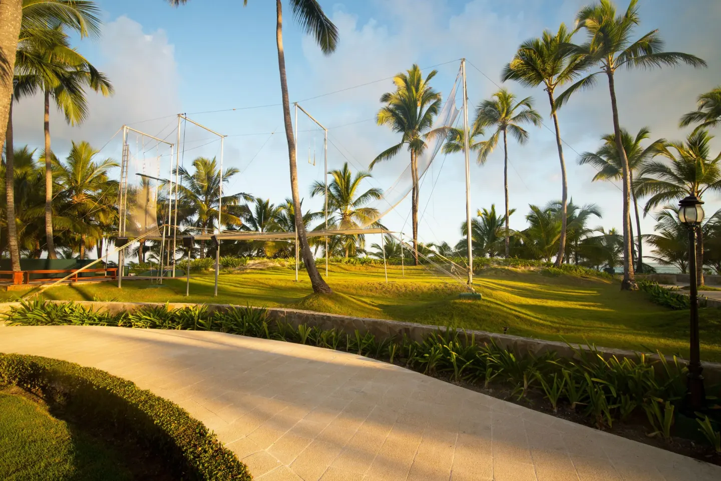 Grassy activity lawn with trapeze structures and palms at Occidental Caribe.