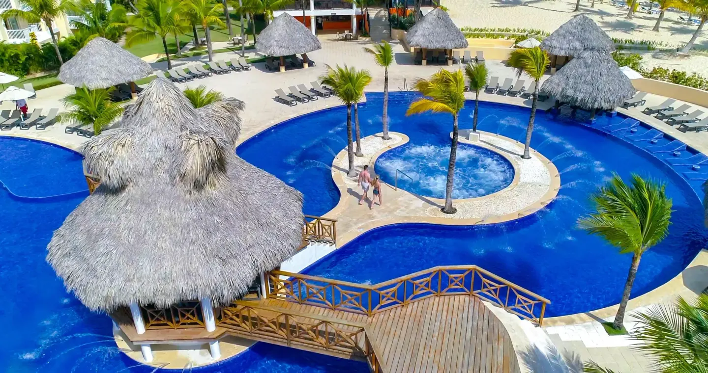 An overhead view of the curving pool, bridge, and thatched pavilions at Occidental Caribe.