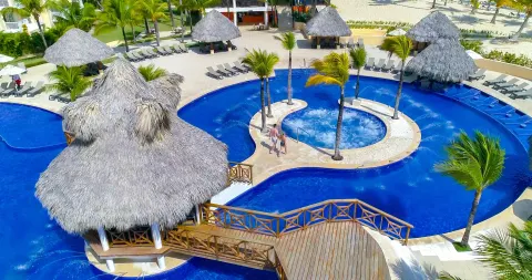 An overhead view of the curving pool, bridge, and thatched pavilions at Occidental Caribe.