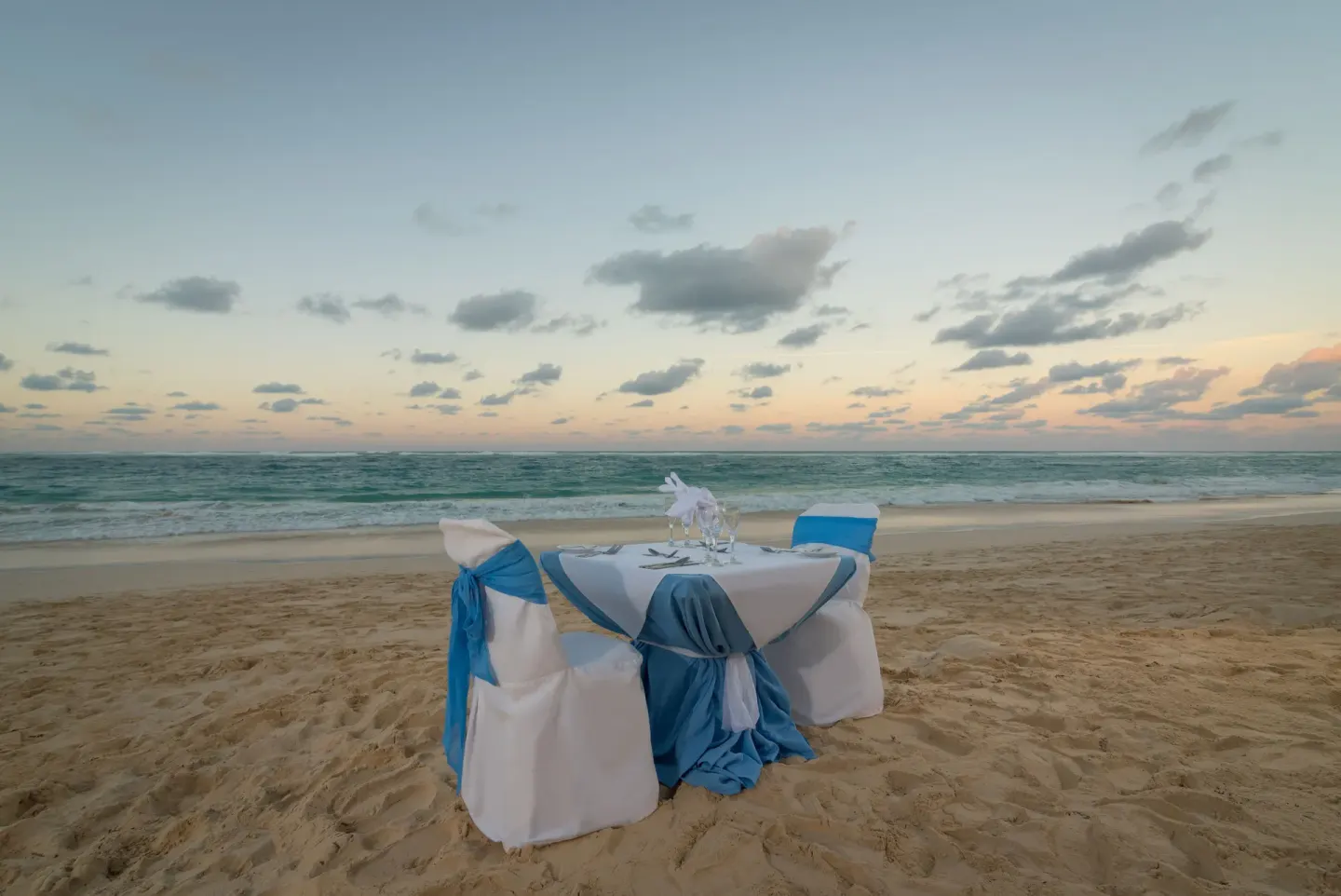 Beach dinner table with blue chair sashes at Occidental Caribe.