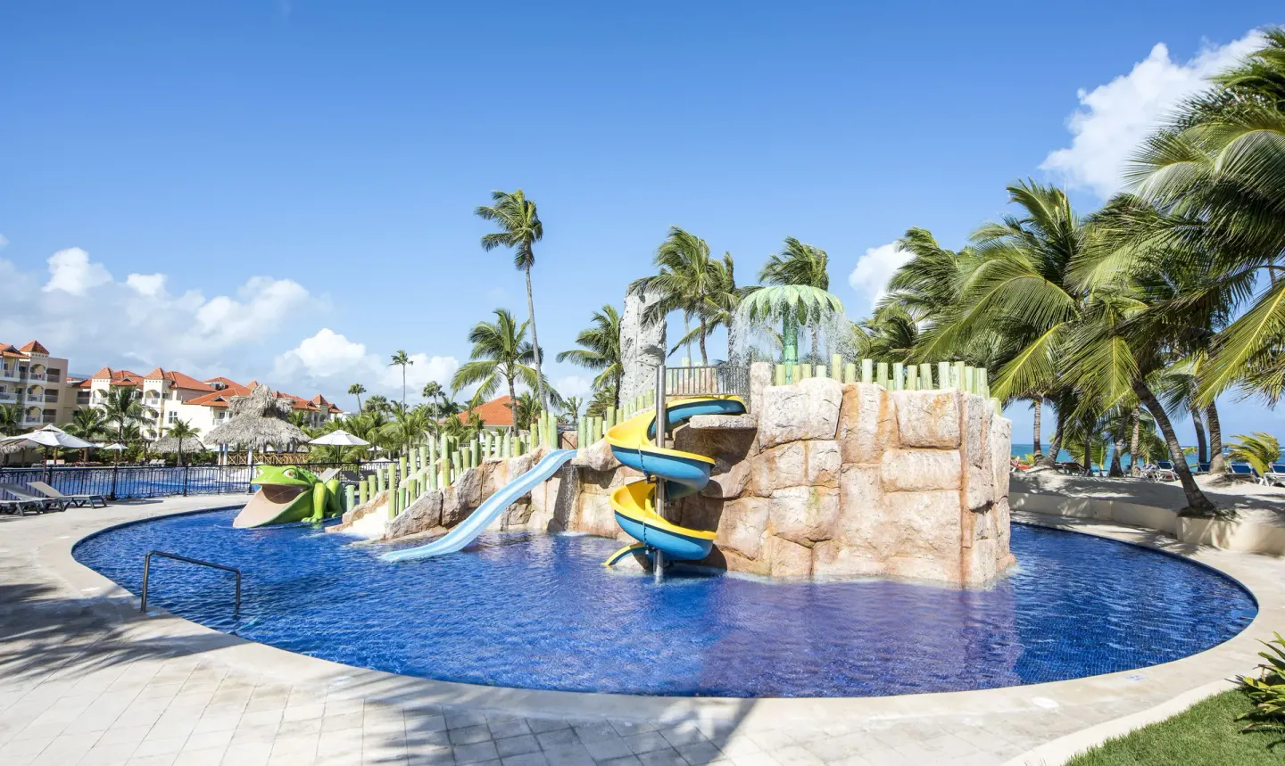 A children's pool with colorful slides and palm trees at Occidental Caribe.