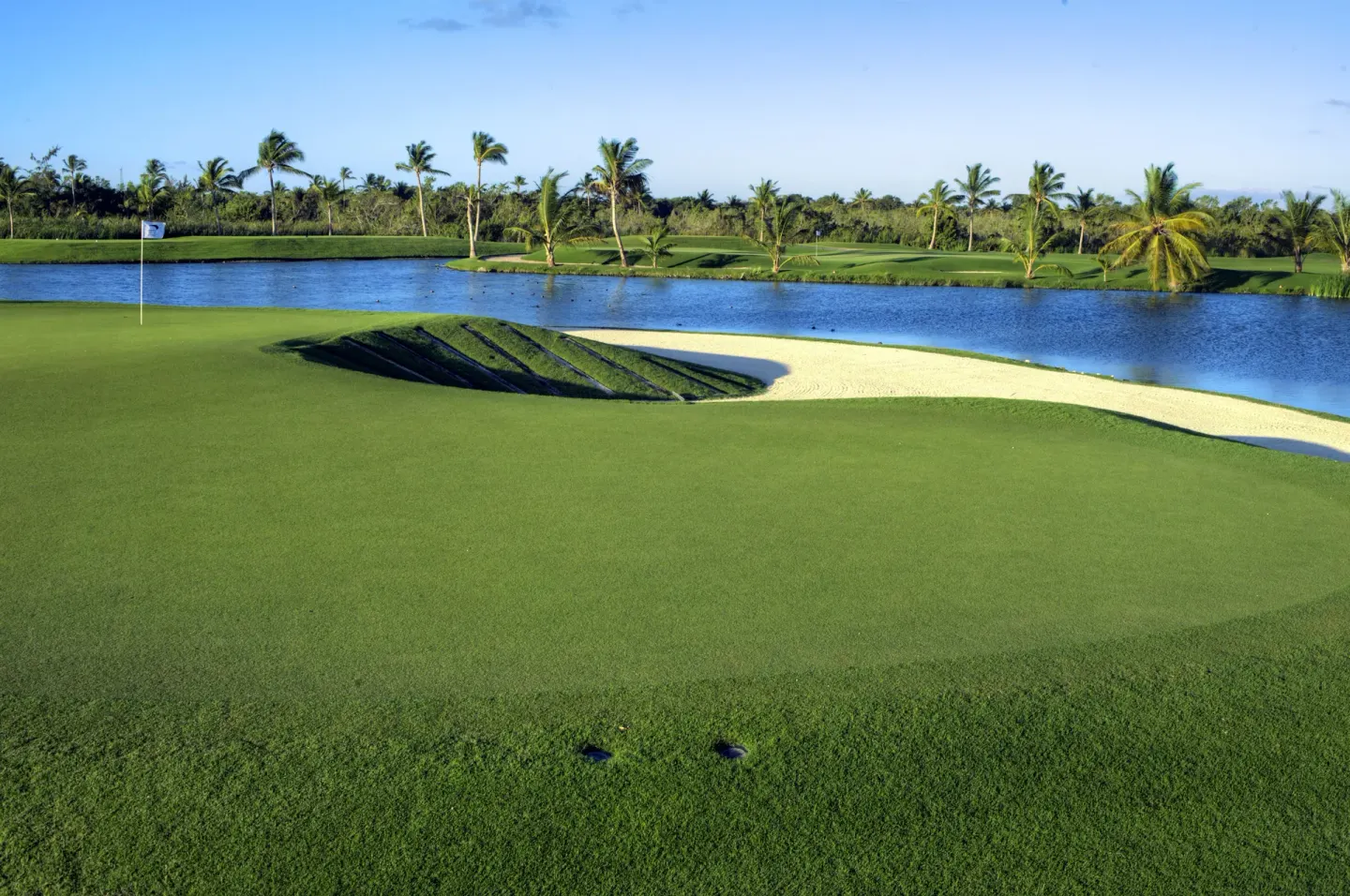 A golf green bordered by sand and a lagoon appears near Occidental Caribe.