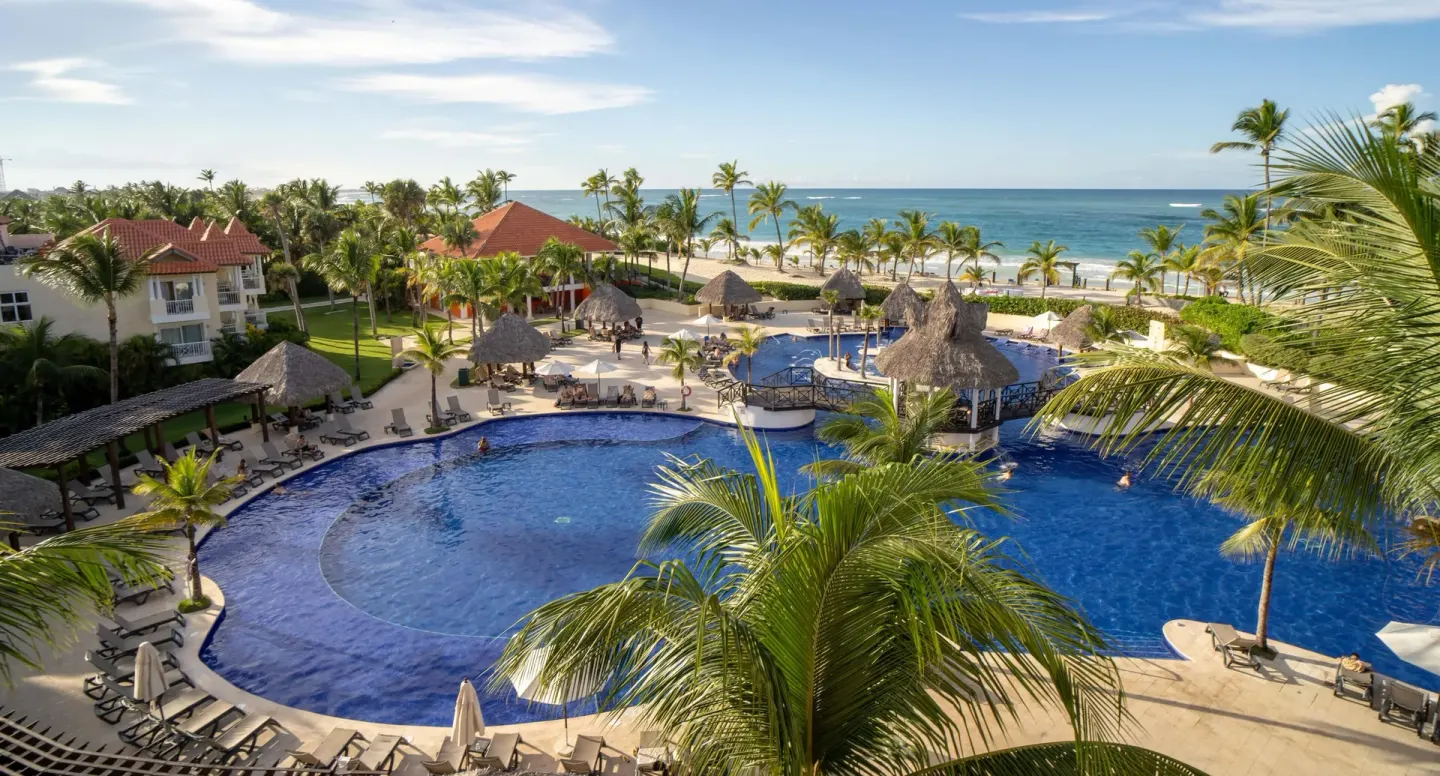 The main pool area overlooks palms, loungers, and the beach at Occidental Caribe.