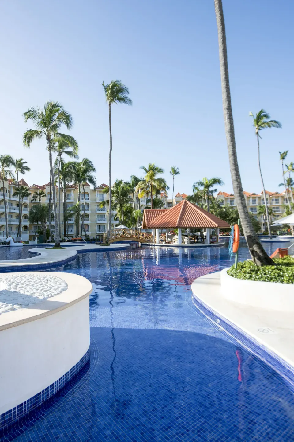 A blue pool with palm islands and a tiled-roof pavilion at Occidental Caribe.