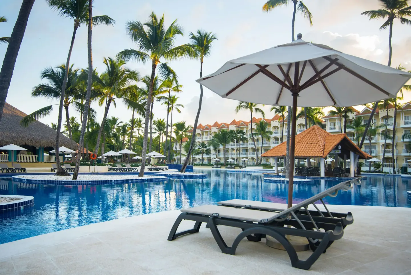 Two loungers under a white umbrella face the pool at Occidental Caribe.