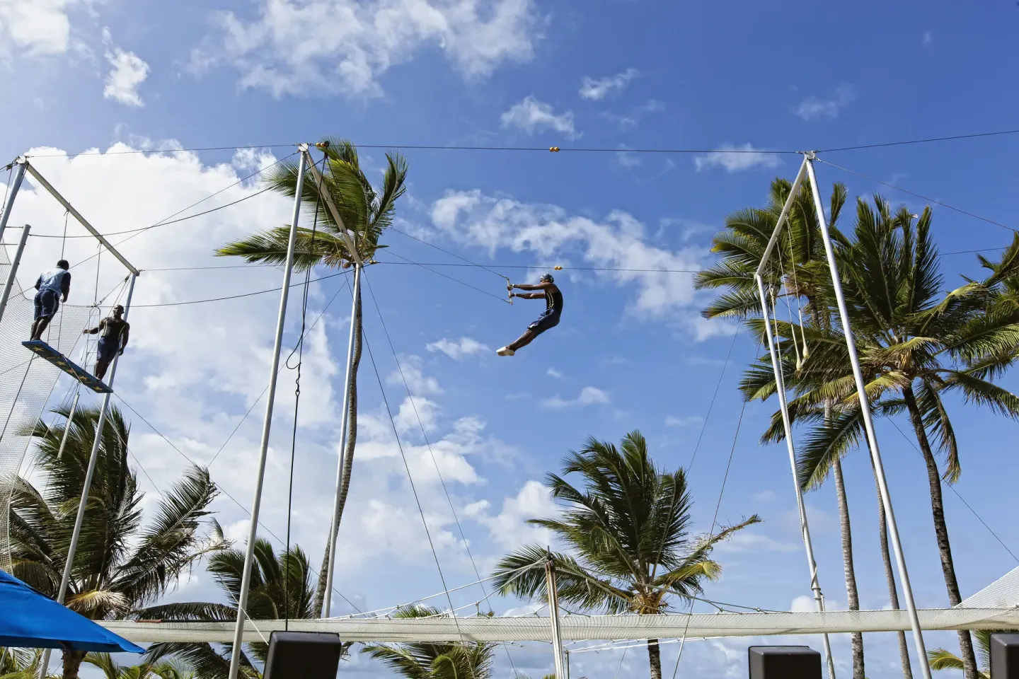 Guest riding a zip line above a netted activity area at Occidental Caribe.