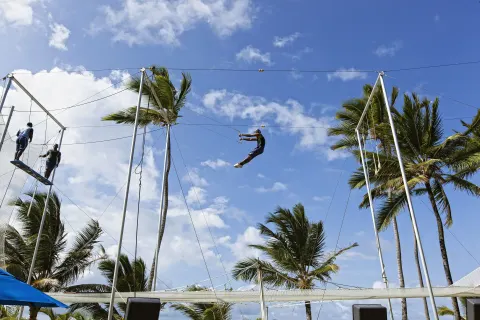 Guest riding a zip line above a netted activity area at Occidental Caribe.