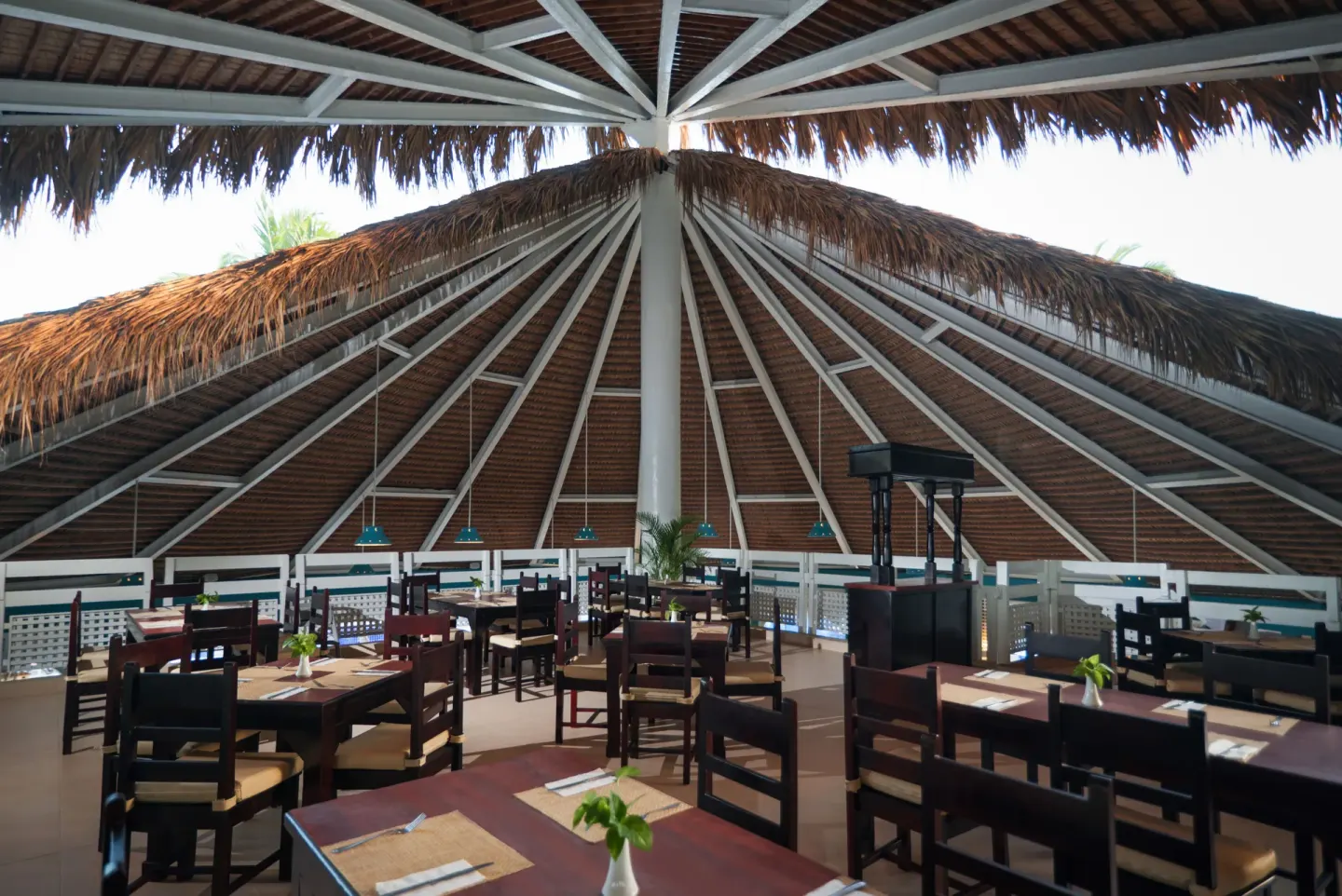 Thatched-roof dining room with wooden tables and chairs at Occidental Caribe.