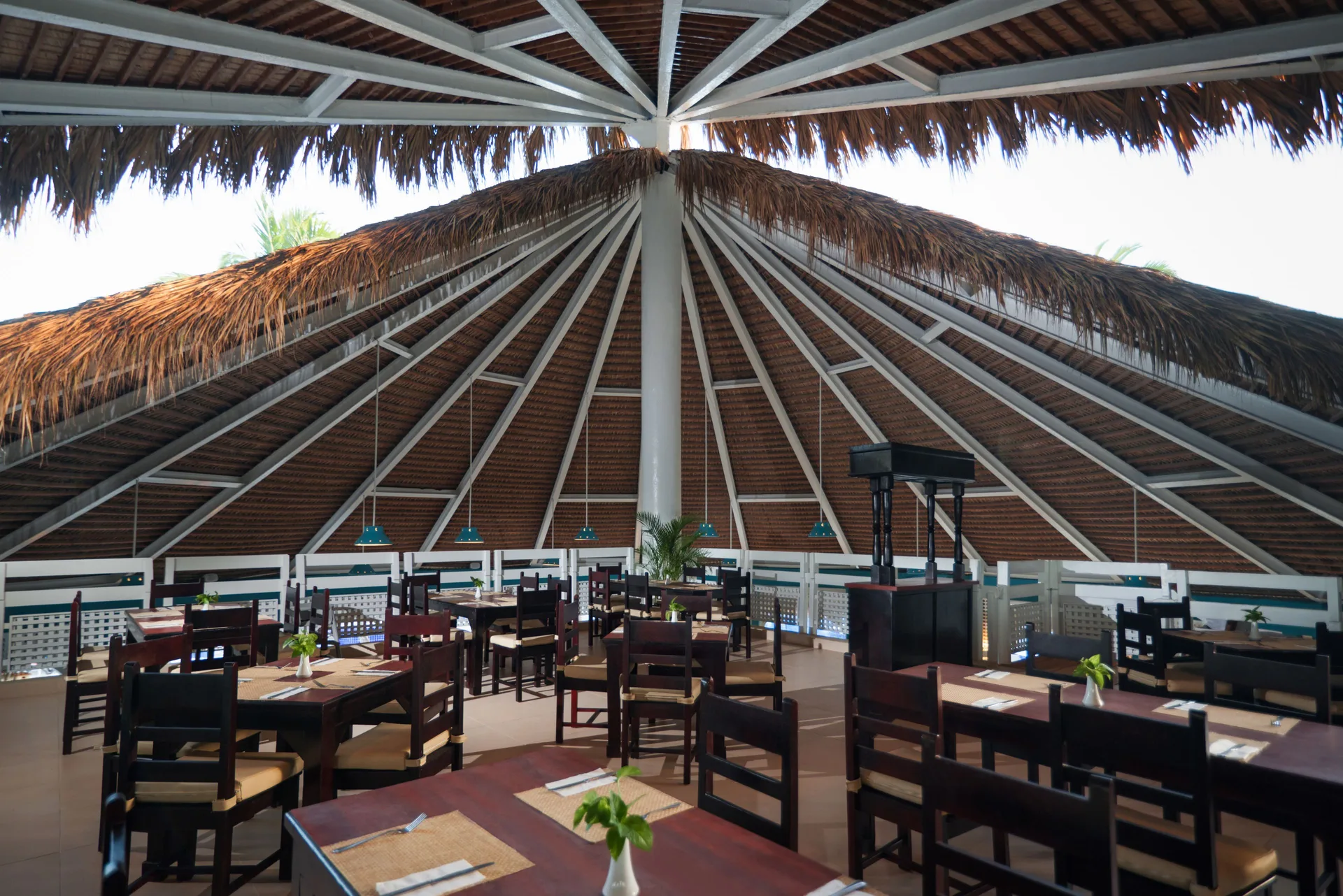 Thatched-roof dining room with wooden tables and chairs at Occidental Caribe.