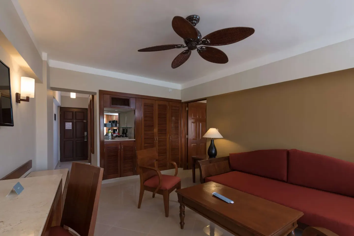 Premium Suite living area with red sofa and wood furnishings at Occidental Caribe.