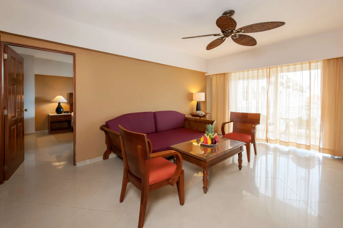 Premium Suite lounge with purple sofa, armchairs, balcony curtains, and fruit at Occidental Caribe.