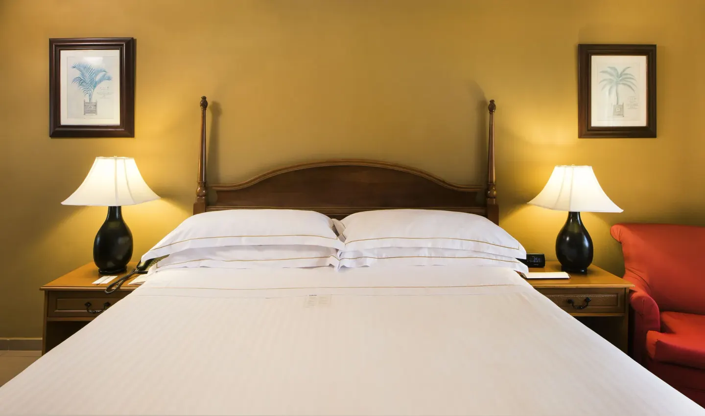 King bed with bedside lamps and a red armchair in an Ocean View room at Occidental Caribe.