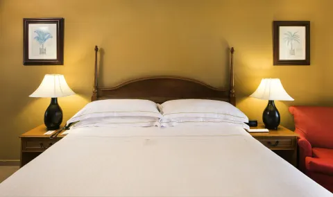 King bed with bedside lamps and a red armchair in an Ocean View room at Occidental Caribe.