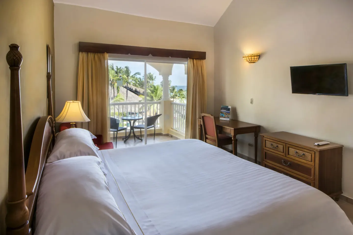 King bed and balcony with palm trees and ocean beyond in an Ocean View room at Occidental Caribe.