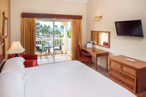 Ocean View room with king bed, balcony seating, desk, and TV at Occidental Caribe.