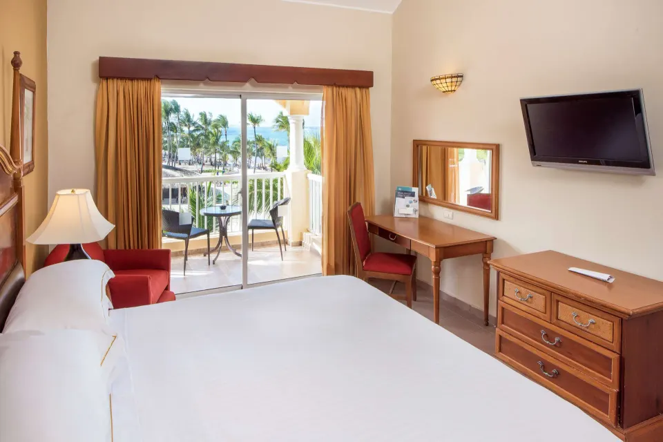 Ocean View room with king bed, balcony seating, desk, and TV at Occidental Caribe.