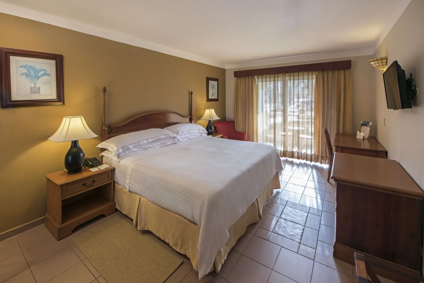 Ocean View room with a king bed, desk, TV, and balcony doors at Occidental Caribe.