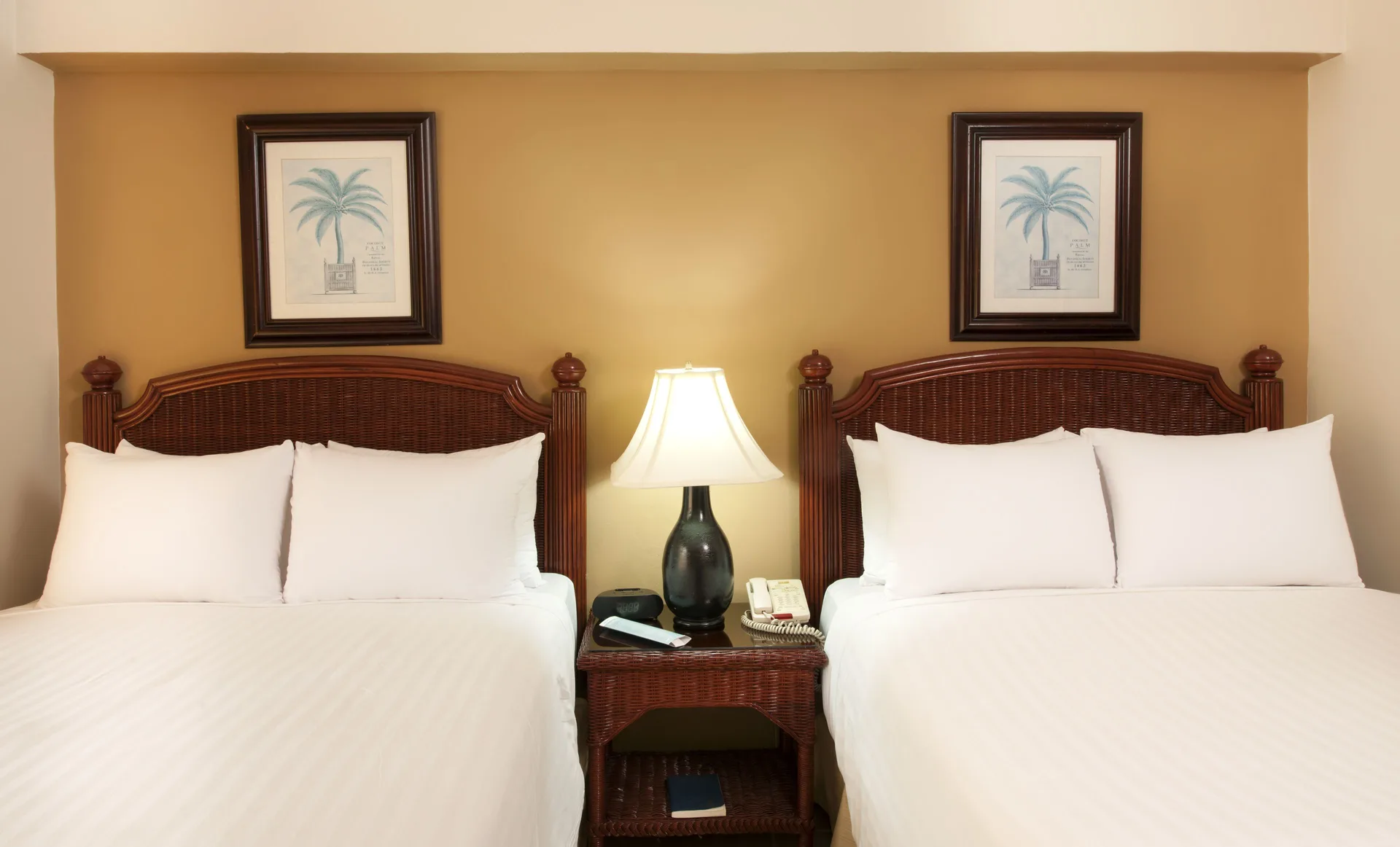 Two white beds with wicker headboards in an Ocean View room at Occidental Caribe.