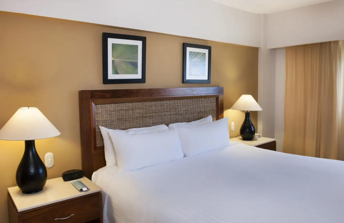 Superior Room king bed with woven headboard and lamps at Occidental Caribe.