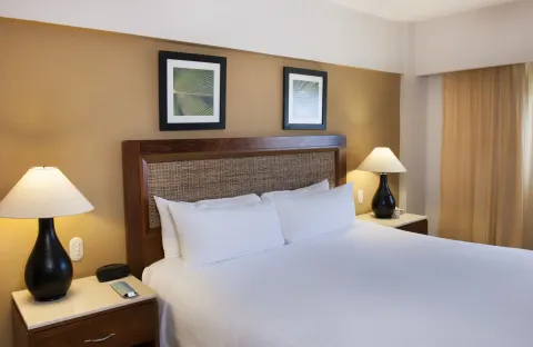 Superior Room king bed with woven headboard and lamps at Occidental Caribe.