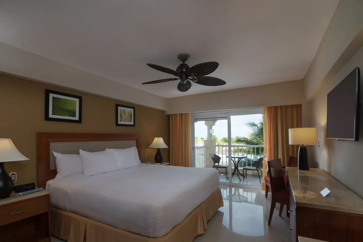 Superior Room with king bed, wall TV, and balcony doors at Occidental Caribe.