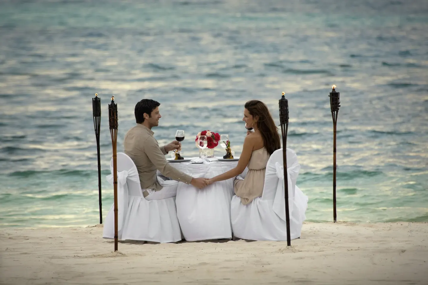 Couple dining at a white table on the beach at Occidental Costa Cancún.