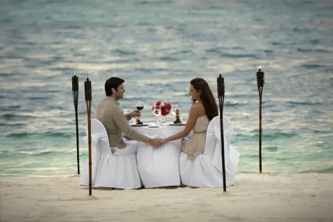 Couple dining at a white table on the beach at Occidental Costa Cancún.