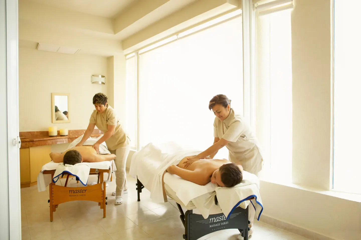 Two massage tables with therapists in a bright spa room at Occidental Costa Cancún.