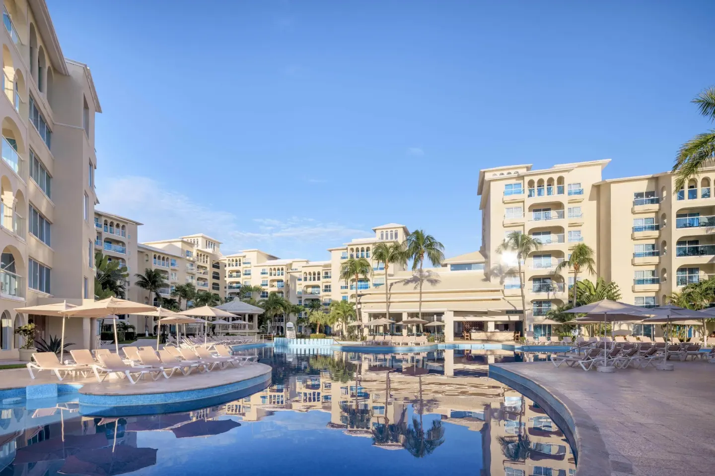 Curving resort pool with loungers and cream buildings at Occidental Costa Cancún.