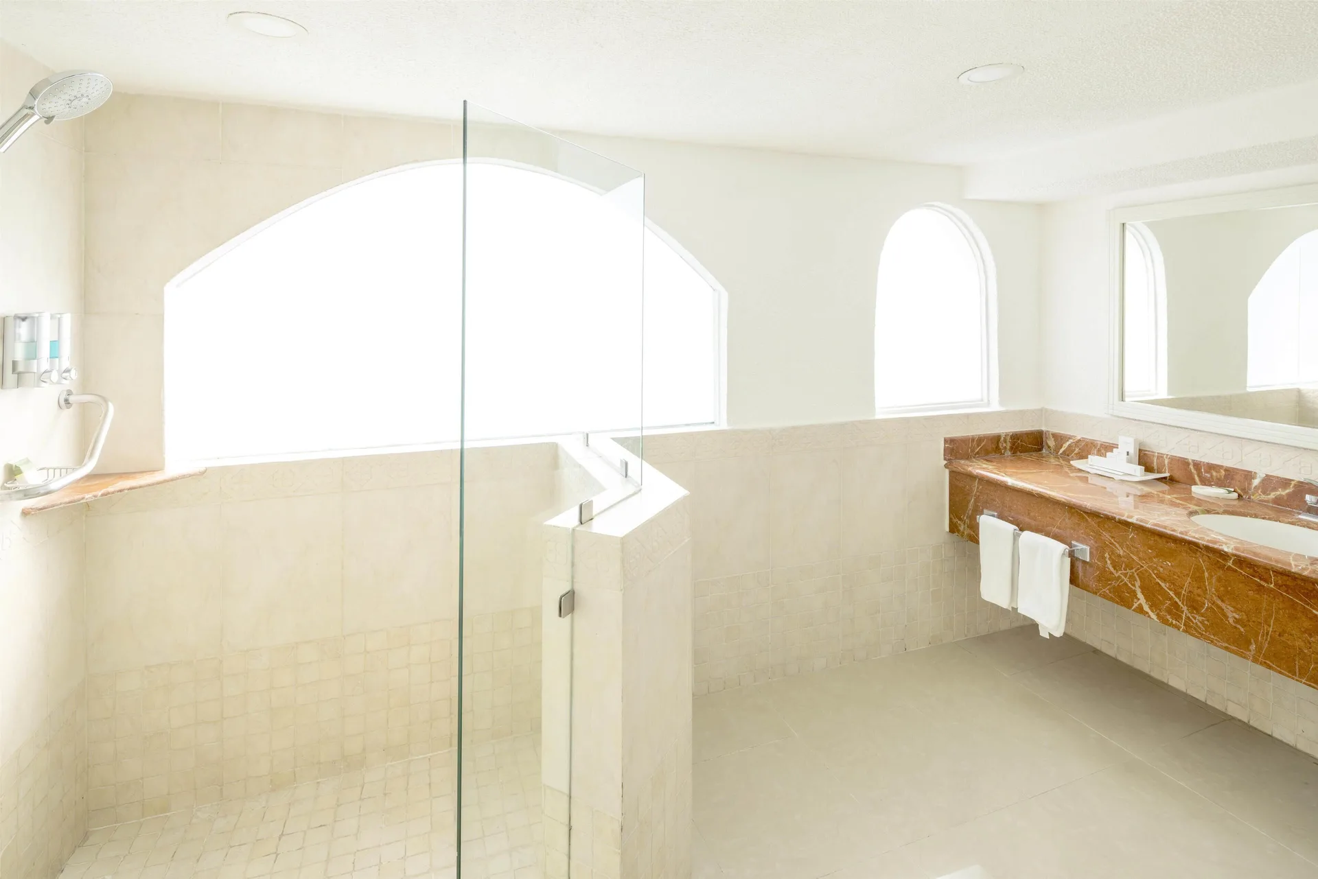 Bright guest bathroom with glass shower and marble vanity at Occidental Costa Cancún.