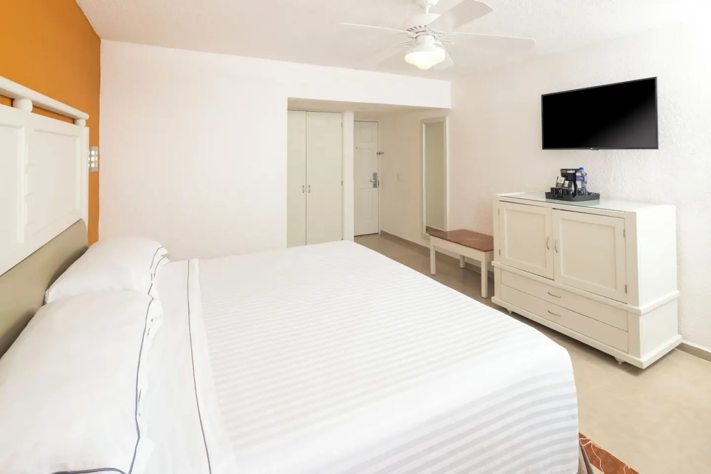 Guest room with a king bed, wall-mounted TV, and white furnishings at Occidental Costa Cancún.