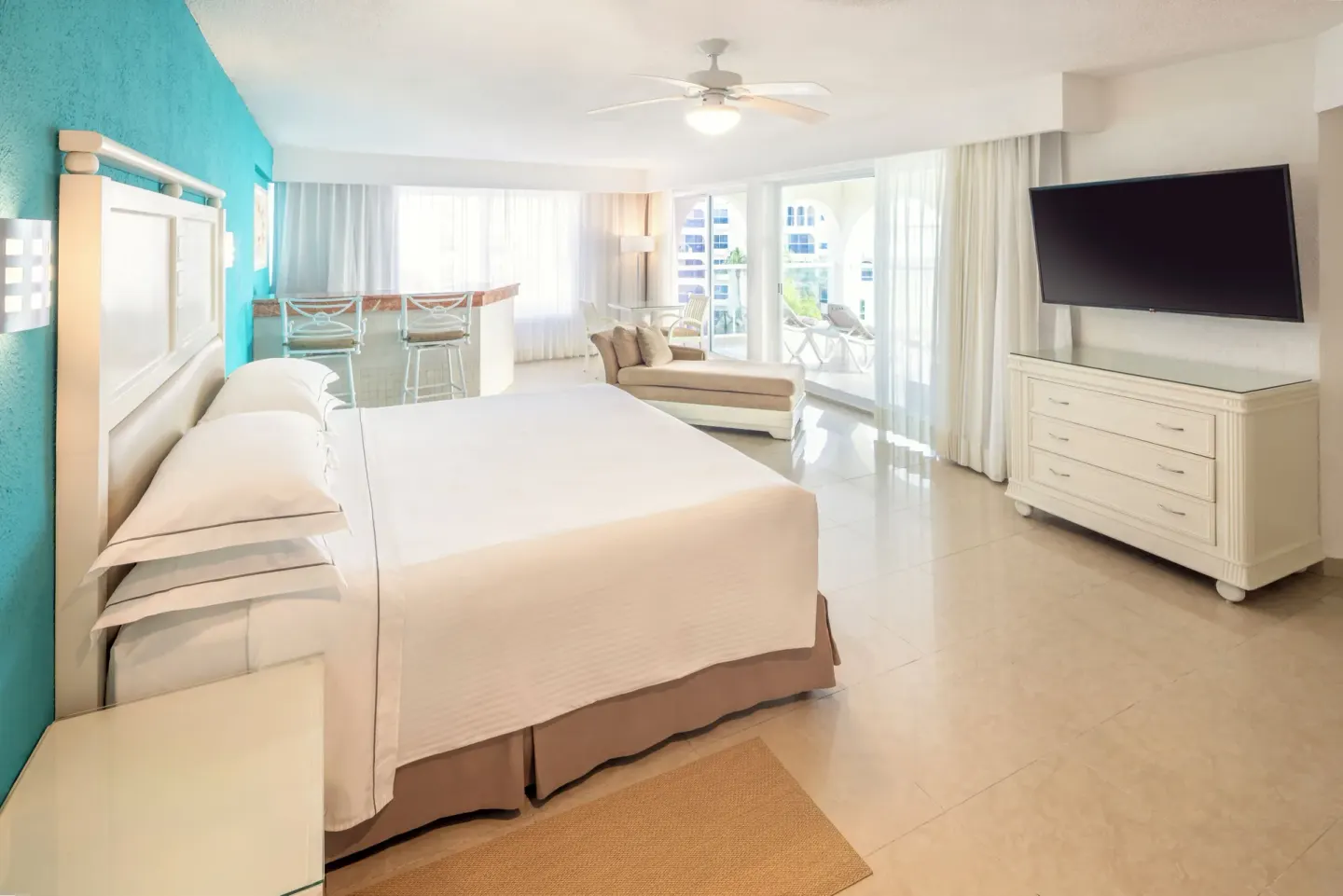 King-bed guest room with turquoise accent wall and balcony light at Occidental Costa Cancún.