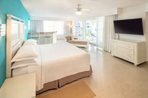 King-bed guest room with turquoise accent wall and balcony light at Occidental Costa Cancún.