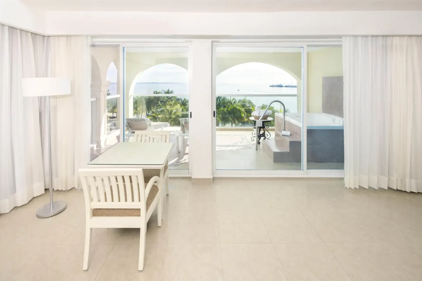 Guest room sitting area with desk, balcony doors, terrace, and sea view at Occidental Costa Cancún.