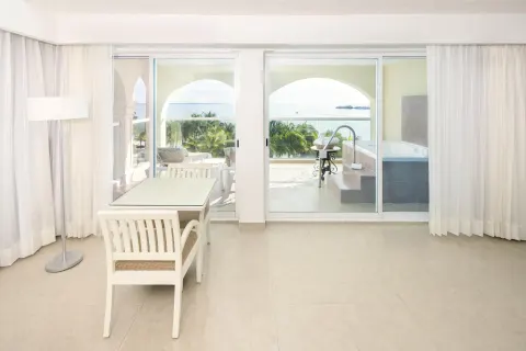 Guest room sitting area with desk, balcony doors, terrace, and sea view at Occidental Costa Cancún.