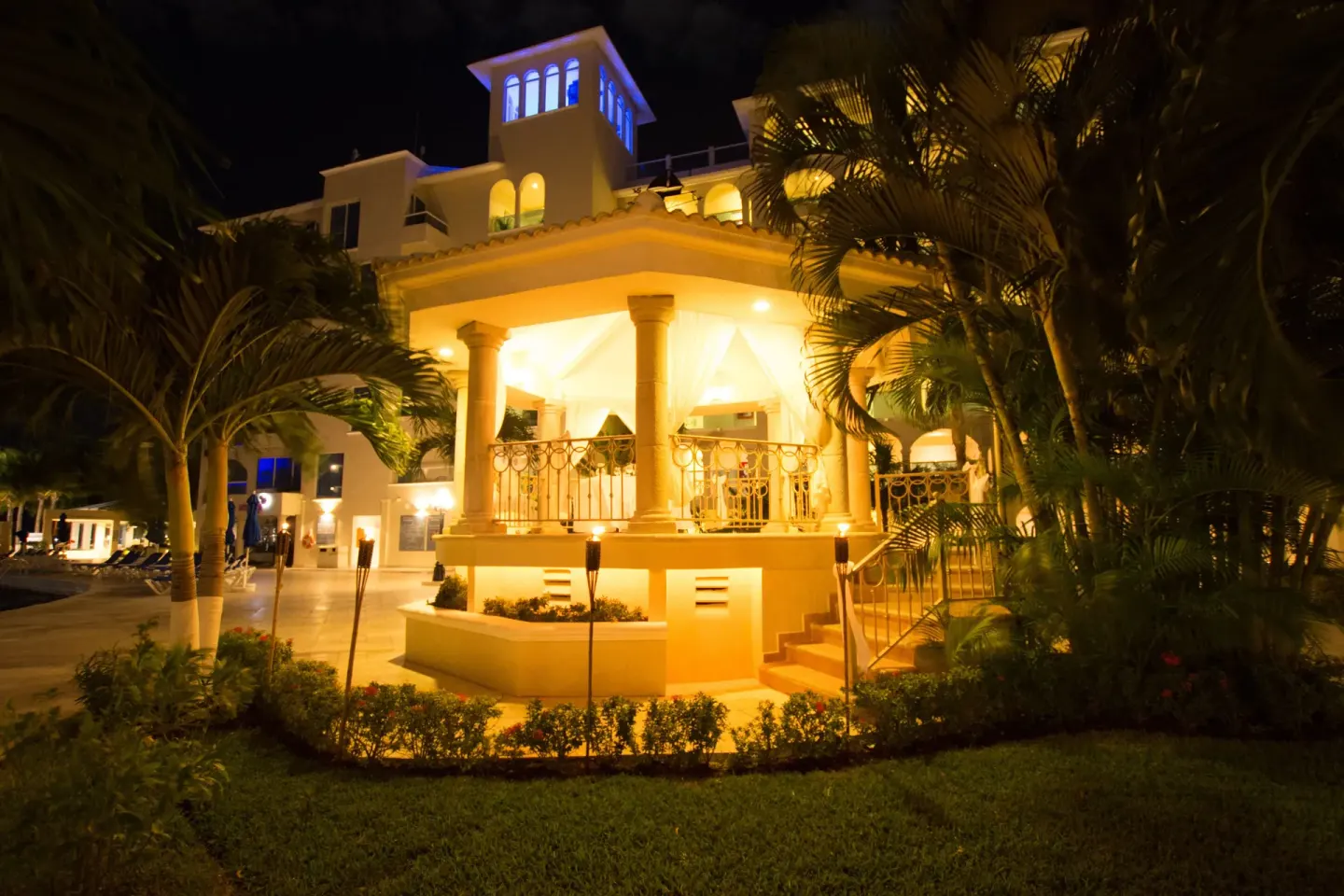 Illuminated garden gazebo and resort building at night at Occidental Costa Cancún.