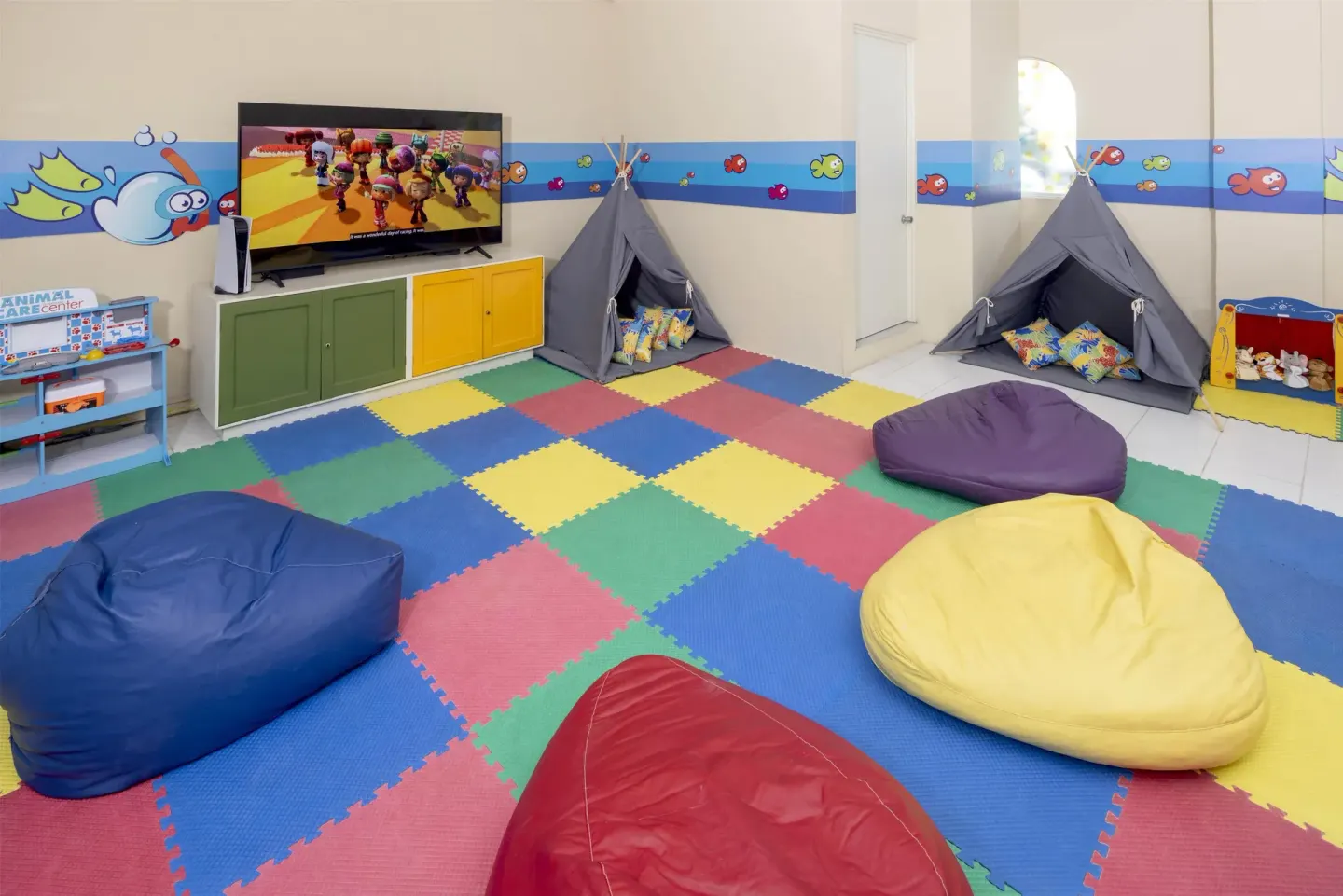 Indoor kids' room with beanbags, teepees and a TV at Occidental Costa Cancún.