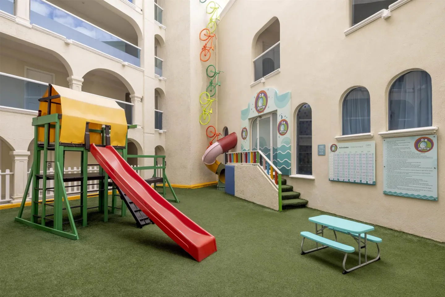 Kids' club courtyard with slides, activity boards and picnic table at Occidental Costa Cancún.
