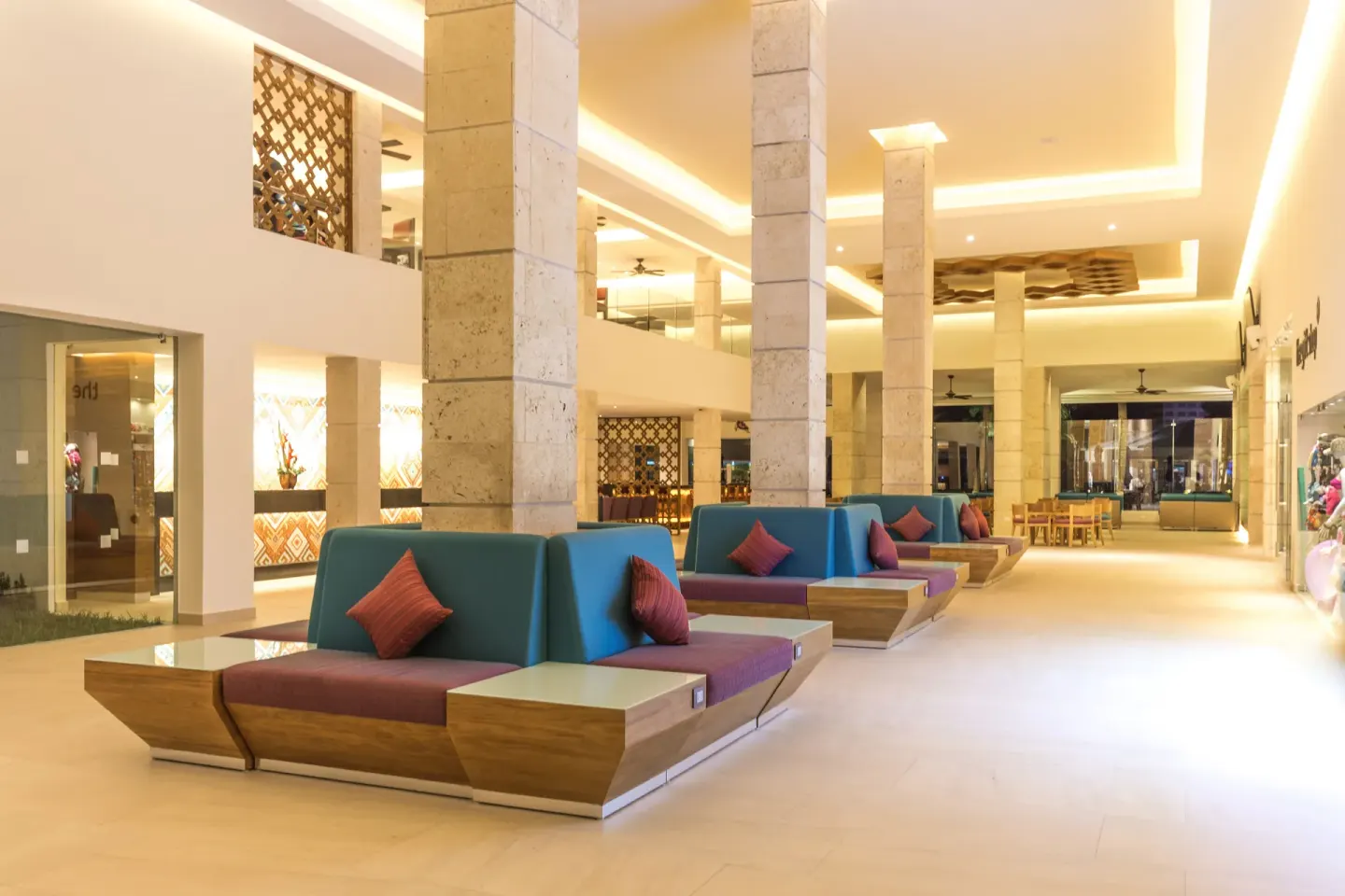 Modern lobby seating with tall stone columns and colorful cushions at Occidental Costa Cancún.