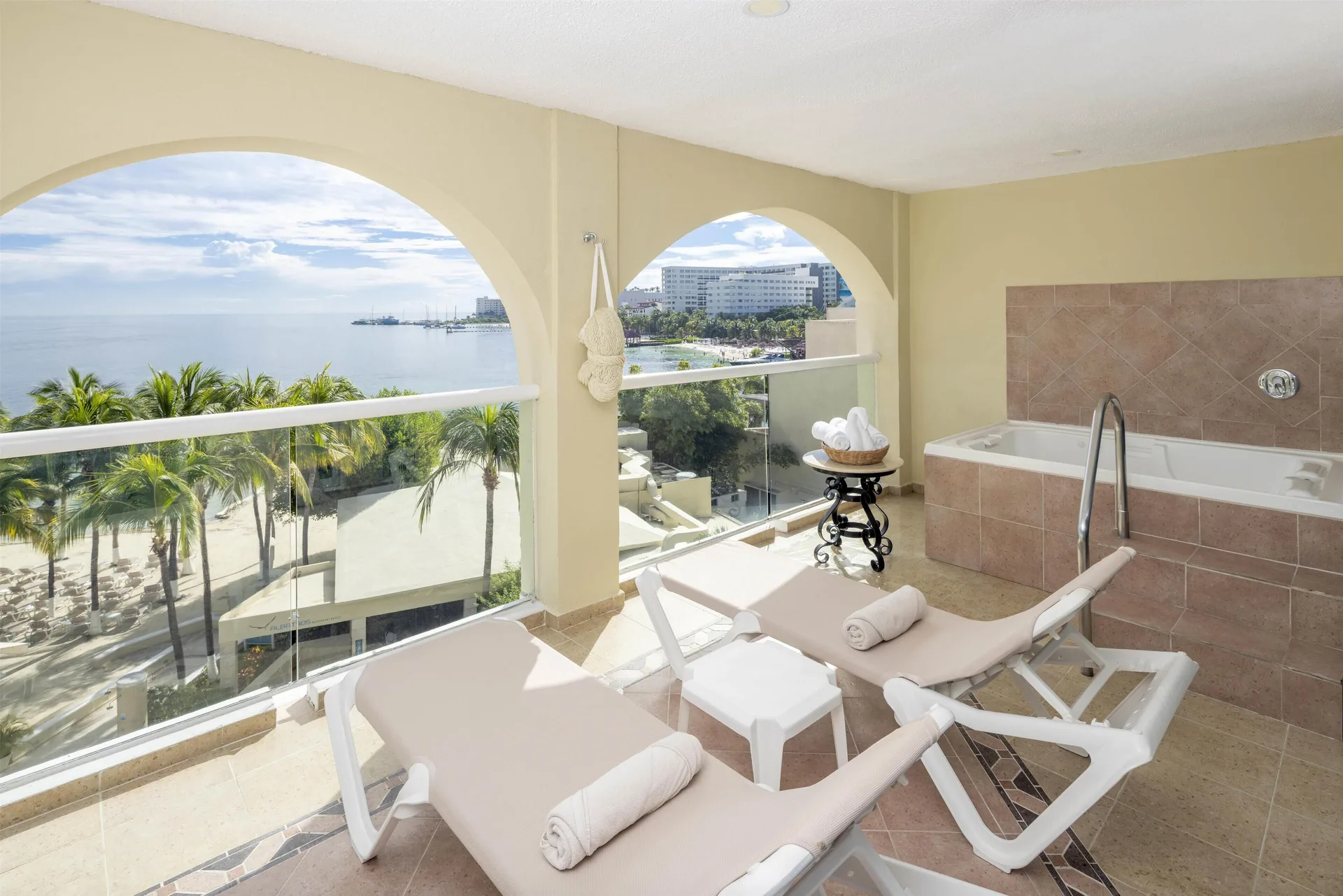 Private terrace with loungers, whirlpool tub, and ocean view at Occidental Costa Cancún.