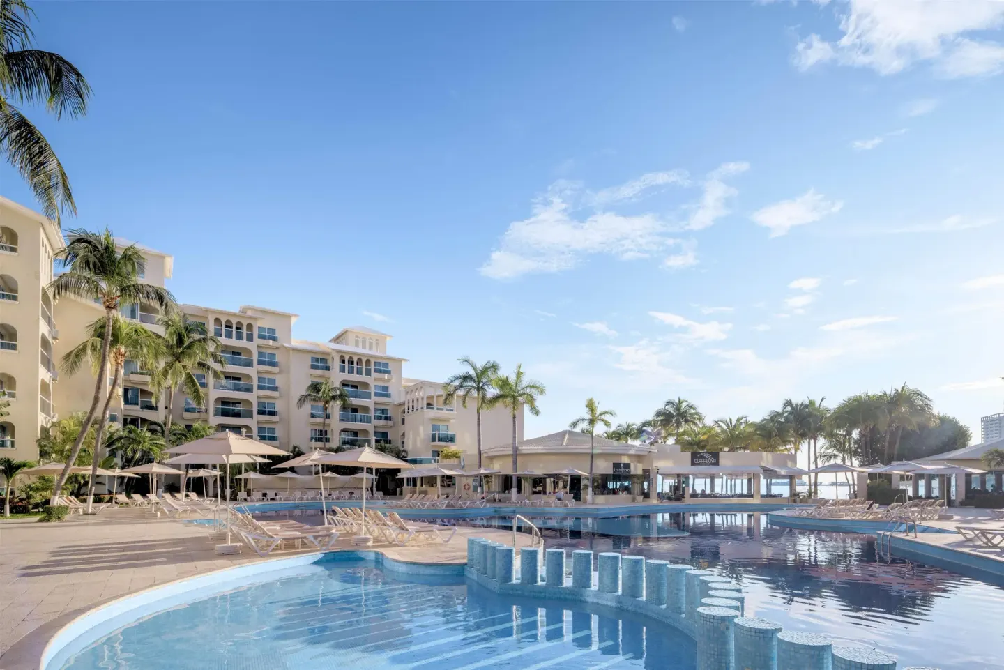 Poolside view with shallow water feature and palm trees at Occidental Costa Cancún.