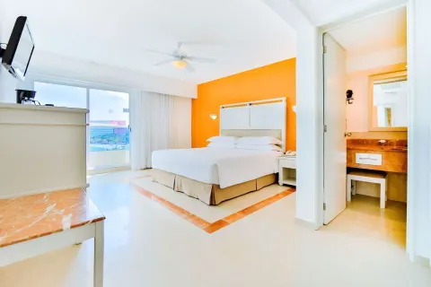 Ocean View room with king bed, balcony doors, and vanity area at Occidental Costa Cancún.