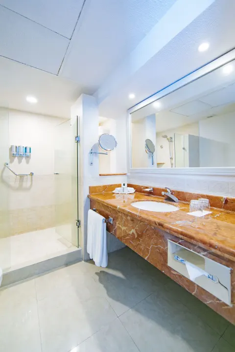Sea View room bathroom with marble vanity and glass shower at Occidental Costa Cancún.