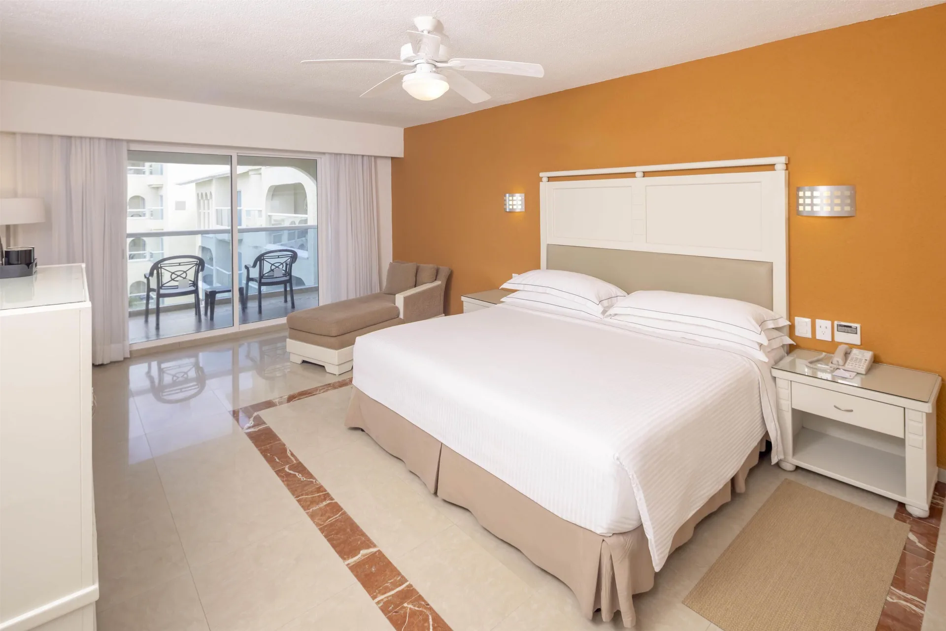 Terrace guest room with king bed and balcony seating at Occidental Costa Cancún.