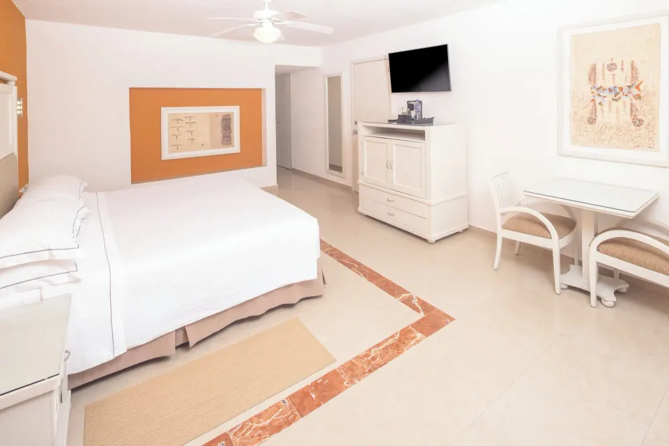 Terrace guest room with king bed, TV cabinet and dining table at Occidental Costa Cancún.