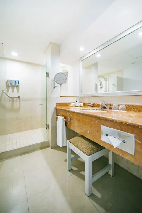 Bathroom for a Room with Terrace at Occidental Costa Cancún with vanity, mirror and glass shower.