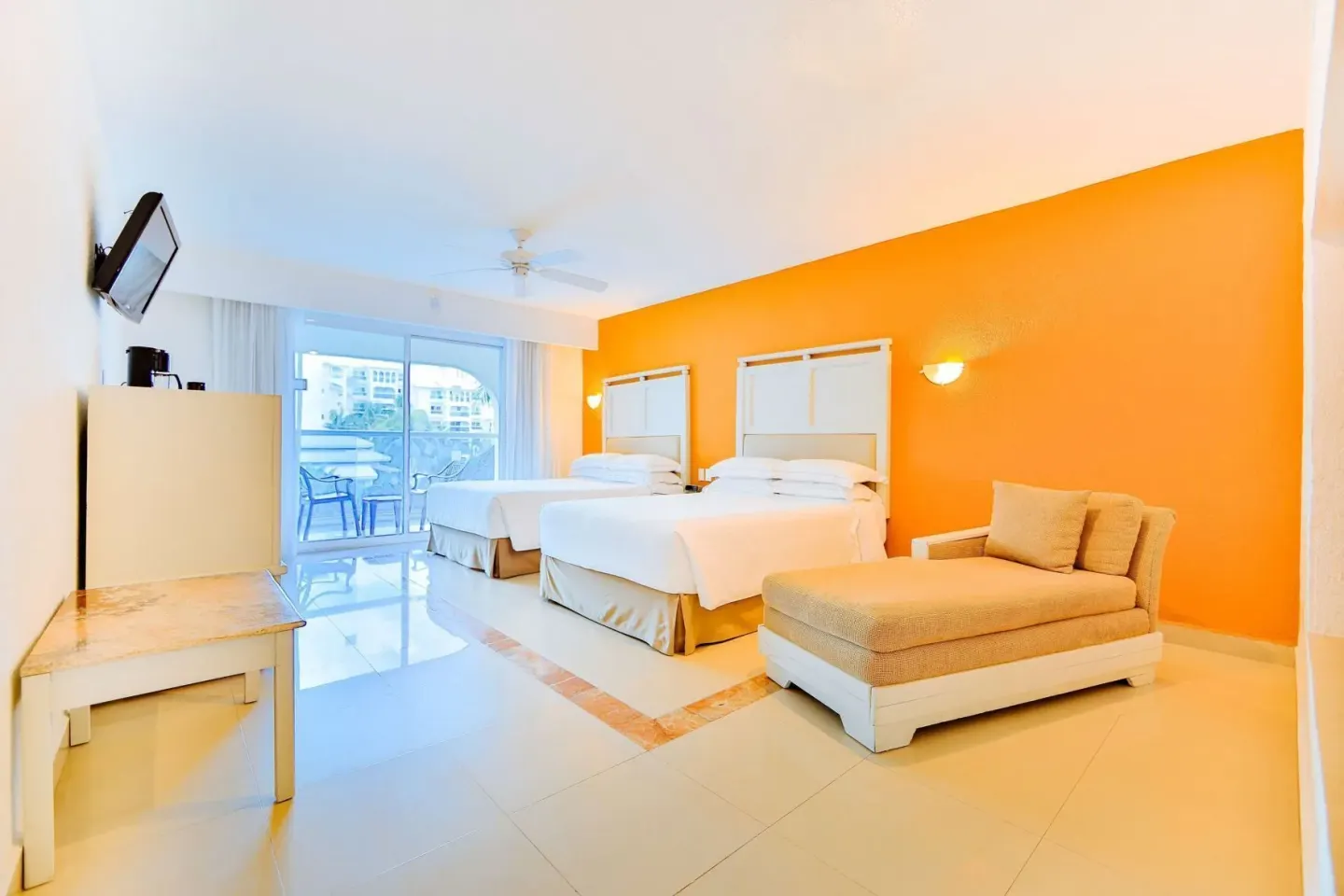 Room with Terrace at Occidental Costa Cancún with two beds, orange wall, chaise lounge and balcony doors.