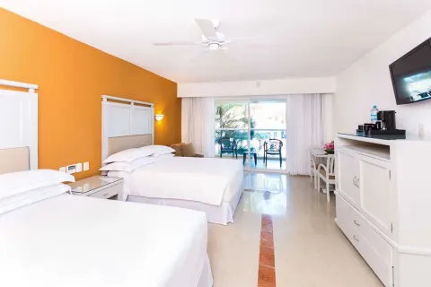 Room with Terrace at Occidental Costa Cancún showing two beds, TV, cabinet and balcony beyond.
